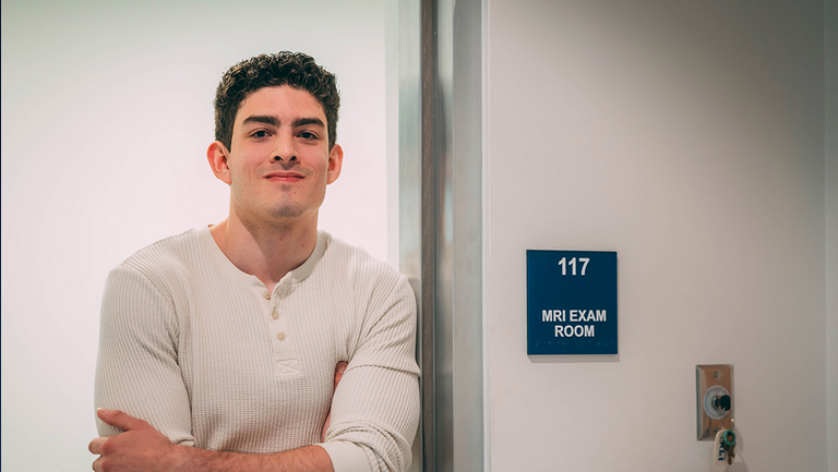 Sebastian Rodriguez, a UNCG nursing student, leaning against the door to an MRI room